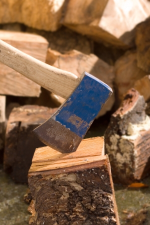 Axe set in wooden block in front of pile of timberの写真素材