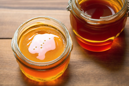 Honey in a glass jar on a wooden background. Selective focus.の素材
