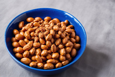 Roasted peanuts in a blue bowl on a gray background, top viewの素材