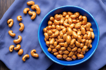 Roasted peanuts in blue bowl on wooden background. Top view.の素材