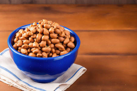 Roasted peanuts in blue bowl on wooden background with copy space.の素材