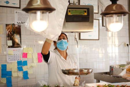 Working portrait of a fishmonger with workers. Three women attending the public. Sale of fish to customers.の写真素材
