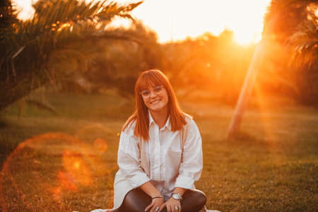 portrait of a red-haired woman with freckles and glasses. Redhead woman in nature. Happy womanの写真素材