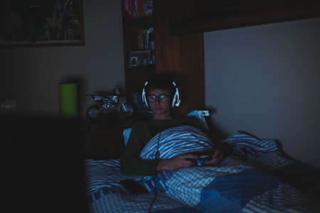 young teenager playing video games on the console. Teen with glasses and acne chatting with her...