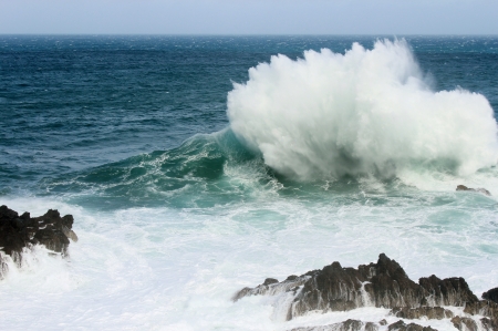 A big wave hitting a rock and crashing into the airの写真素材
