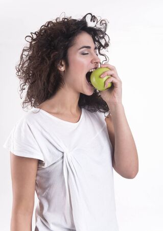 Beautiful young woman eating an apple の写真素材