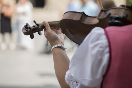 Rear view of a polish woman of a folk dance group with traditional costume playing the violinのeditorial素材