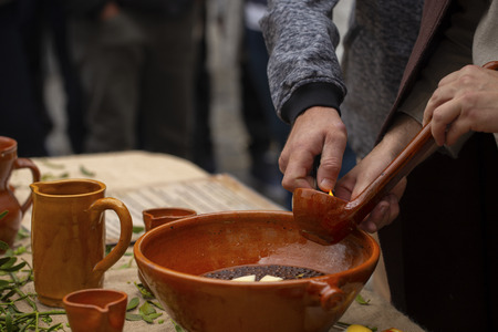 A man is preparing burnt (traditional Galician hot drink made with flamed orujo, sugar and lemon)