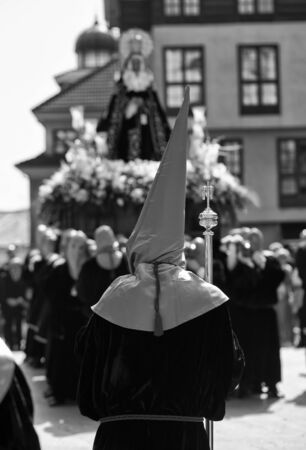 Rear view of a hooded person and Virgin Mary statue behindの写真素材