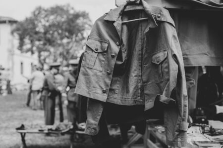 Military jacket hanging and blurred solders behindの写真素材