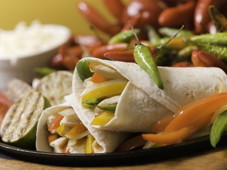 fajitas chicken on iron cooking plate with red and green hot pepper in the background. Shallow depth of field. の写真素材