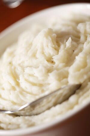 mashed potato in a white bowl with spoon. Very shallow depth of field.の写真素材