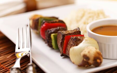 Tasty beef kebab with pepper and onion. Rice and sauce on the side. Very shallow depth of field. Focus on the second piece of meat.の写真素材