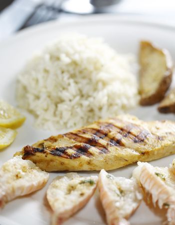 grilled chicken breast with scallop, rice and potato on the side. Very shallow depth of field.の写真素材