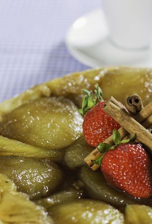 French style apple pie with stawberry and cinnamon on the top.Coffee cup in the background. Shallow depth of field.の写真素材