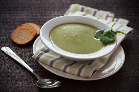 Vegetarian spinach cream soup on a dark background. Leaves and bread on the side.の写真素材