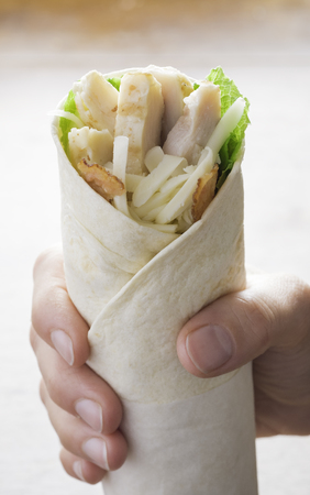 Chicken wrap in a hand with salad and bacon. Healthy food.の写真素材