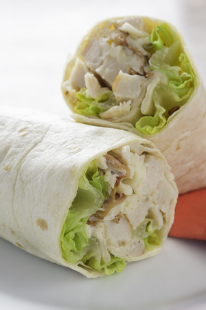 Chicken wrap with salad letuce in a white plate. Red napkin.の写真素材