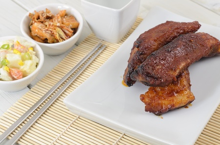 Daeji Galbi - Grilled Korean pork ribs served with gamja salad  potato salad , baechu geotjeoli  seasoned cabbage  and soju の写真素材