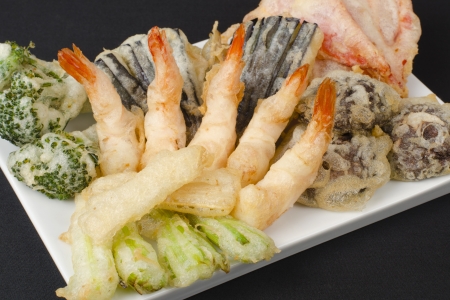 Tempura - Japanese deep fried prawns and assorted vegetables  shiitake mushrooms, peppers, spring onions, aubergine, broccoli and bamboo shoots  on a black background の写真素材