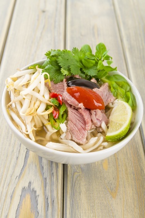 Pho Bo - Vietnamese fresh rice noodle soup with beef, herbs and chili topped with hoisin and chill...