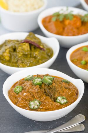 Bhindi Masala - Spiced okra in thick gravy. Chapattis and other vegetarian curries on background.の写真素材