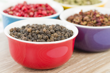 Peppercorns - Black, szechuan, pink and green dried peppercorns in colourful bowls.の写真素材