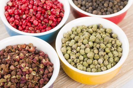 Peppercorns - Szechuan, pink, green and black dried peppercorns in colourful bowls.