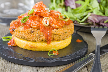 Polenta, Fishcake  Spicy Prawns - Crispy polenta round topped with chorizo fishcake and prawns in tomato and chili sauce garnished with spring onion. Served with salad.の写真素材