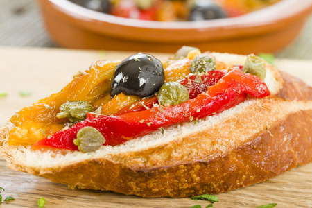 Pimientos Asados Tapas - Spanish roasted pepper salad with olive oil, vinegar, garlic, capers and black olives on crusty bread. Traditional Spanish food.の写真素材