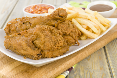 Fried Chicken  Chips - Chicken pieces on the bone coated in a spicy flour and deep fried served with fries, baked beans and gravy.の写真素材