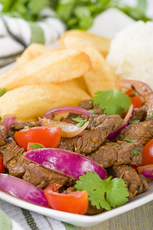 Lomo Saltado - Traditional Peruvian stir-fry with beef, red onions, tomatoes and fries garnished with parsley and coriander.の写真素材