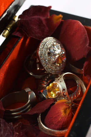 Silver rings and rose petals in a lined jewellery box.の写真素材