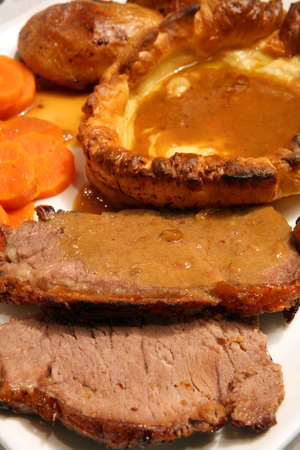 Extreme close-up on a traditional English Sunday lunch of roast beef and yorkshire pudding, with carrots, roast potato and gravyの写真素材