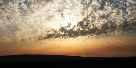 The sun behind clouds, low over sand dunes in the Arabian desert.の写真素材
