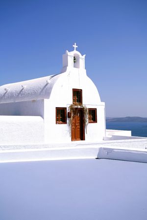 An orthodox greek chapel, in Oia on Santorini, against a bright blue sky.の写真素材