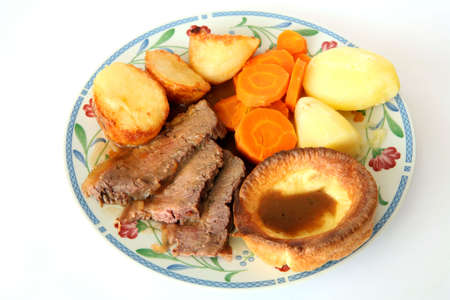 Traditional British Sunday lunch of roast beef, Yorkshire pudding, roast and boiled potato, carrots and gravyの写真素材