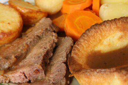 Extreme close-up on a dinner of roast beef and Yorkshire pudding, with roast and boiled potatoes and carrots.の写真素材