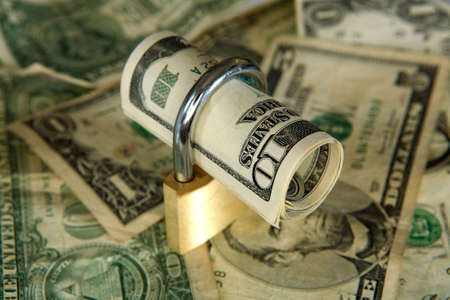 US dollars secured with a padlock on an out-of-focus dollar backgroundの写真素材