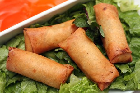 Spring rolls on a bed of lettuce, with a sweet and sour dip