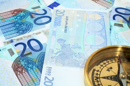 A compass, showing North, on a background of 20 euro banknotes - symbolic of finances being on the right course. の写真素材