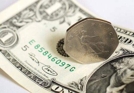 A British 50 pence piece on a US one dollar bill, the two are roughly equivalent in value in early 07.の写真素材