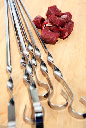 Barbecue skewers on a chopping board with chopped cubes of beef.の写真素材