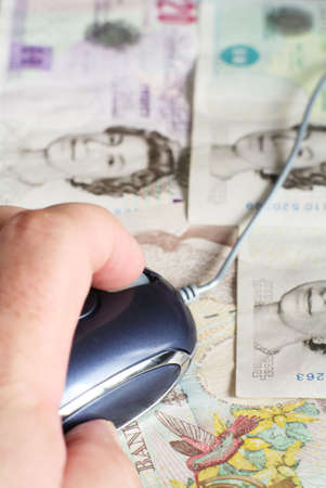 A hand with a mouse on an array of British banknotes, symbolising  earning money with a computer.