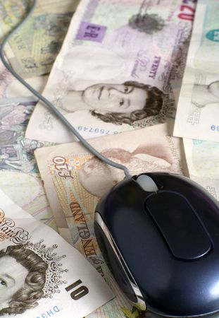 A computer mouse on an array of British banknotes, symbolic of earning money using  comuters.の写真素材