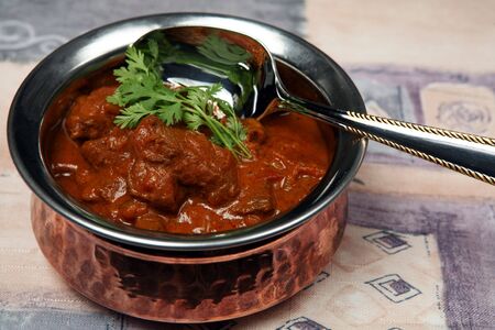 A serving bowl full of Madras butter beef curry.の写真素材