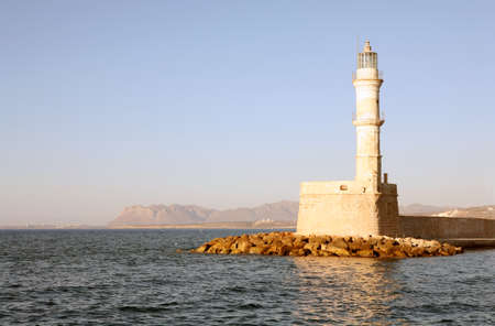 The lighthouse at the harbour entrance in Hania, Crete, with the hills of the Akrotiri Peninsula behind it.の写真素材