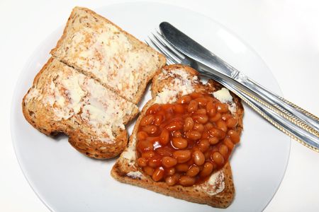 Beans on buttered toast with a knife and fork - a cheap, everyday mealの写真素材