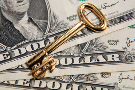 US currency notes with a gold key, its end in the shape of the dollar symbol. conceptual for locking in profit or unlocking wealth.の写真素材