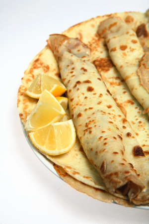 A pile of English-style pancakes (also called crepes) on a plate with slices of lemon. The pancakes are served, usually with lemon and sugar, on Shrove Tuesday (Mardi Gras) as well as being year-round treat.の写真素材